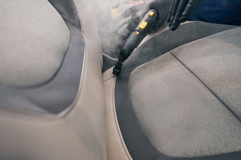 Closeup steam cleaner in worker hand. Dry cleaning of leather seat. Detailing car service. Car care