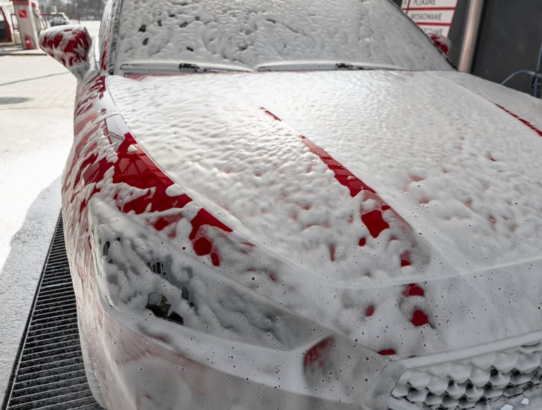 Close-up of the front of a car being washed with active foam at a touchless car wash