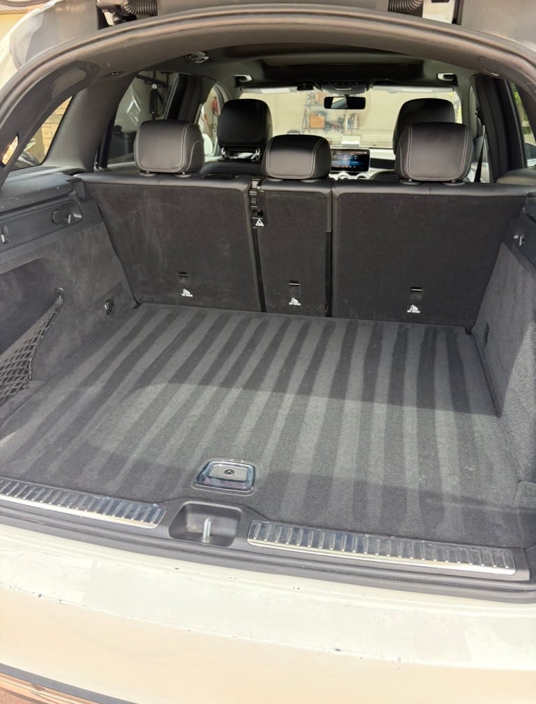 Interior view of empty car trunk with gray ribbed cargo mat and rear seats folded down