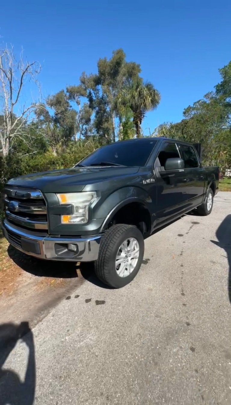 Dark blue Ford F-150 pickup truck parked on a residential street with trees in the background