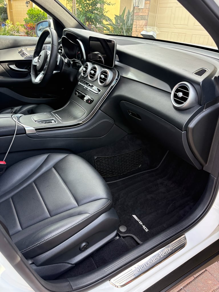 Interior view of a luxury car showing black leather seats, steering wheel, digital dashboard, and air vents